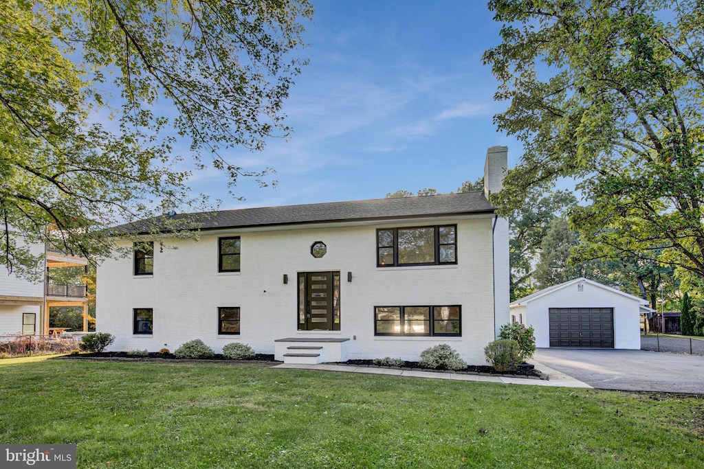 split foyer home with a front lawn, an outbuilding, and a garage