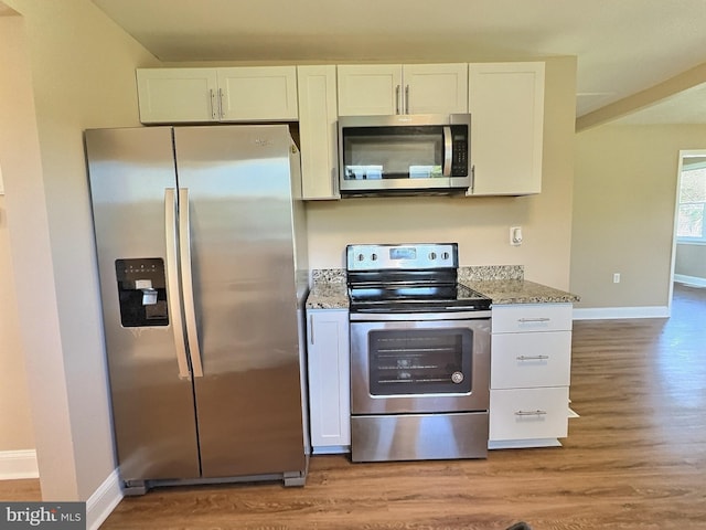 kitchen featuring appliances with stainless steel finishes, stone counters, light hardwood / wood-style floors, and white cabinetry