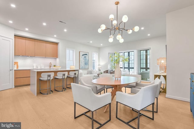 dining room with light hardwood / wood-style flooring and a notable chandelier