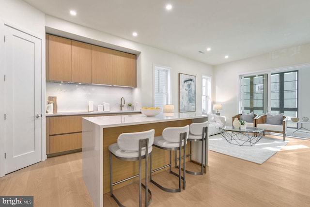 kitchen featuring a kitchen breakfast bar, a kitchen island, light hardwood / wood-style floors, and sink