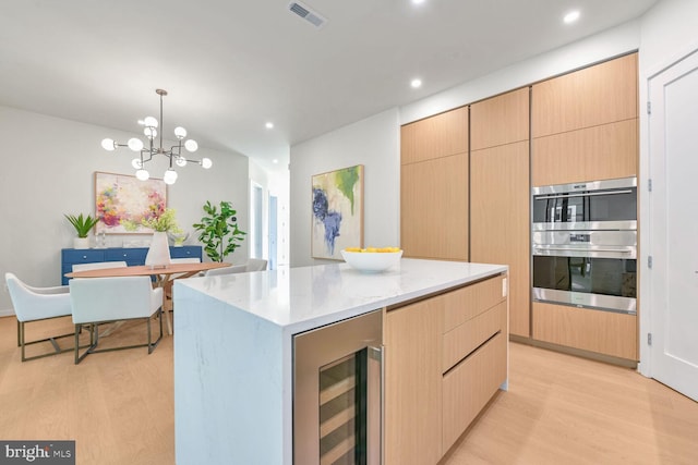 kitchen with wine cooler, light hardwood / wood-style flooring, double oven, decorative light fixtures, and a kitchen island