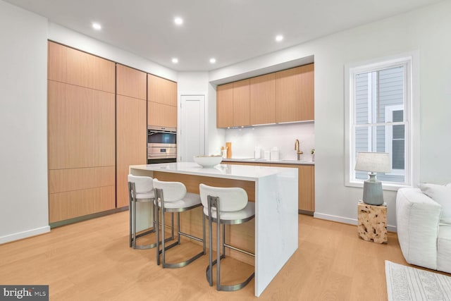 kitchen featuring a kitchen breakfast bar, a center island, light hardwood / wood-style floors, and light brown cabinets