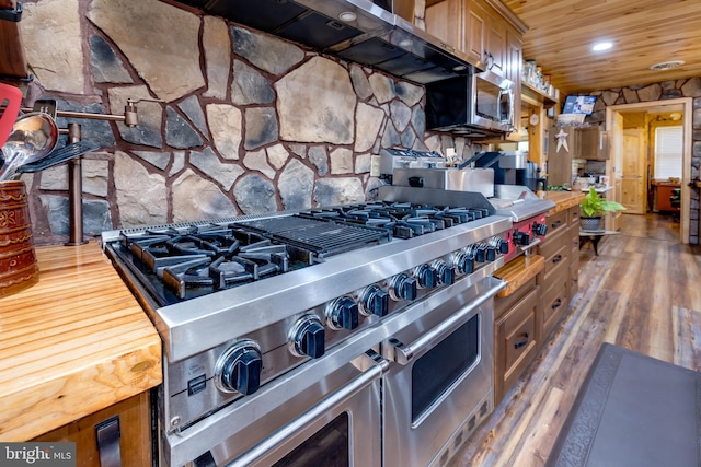 kitchen with appliances with stainless steel finishes, wood counters, and dark hardwood / wood-style flooring