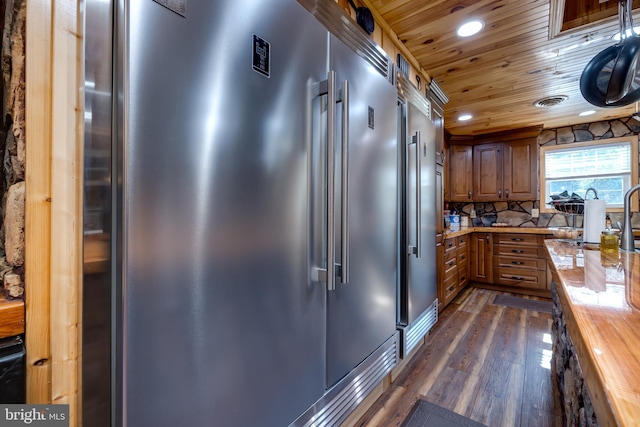 kitchen featuring wood ceiling, high end fridge, dark wood-type flooring, wood counters, and sink