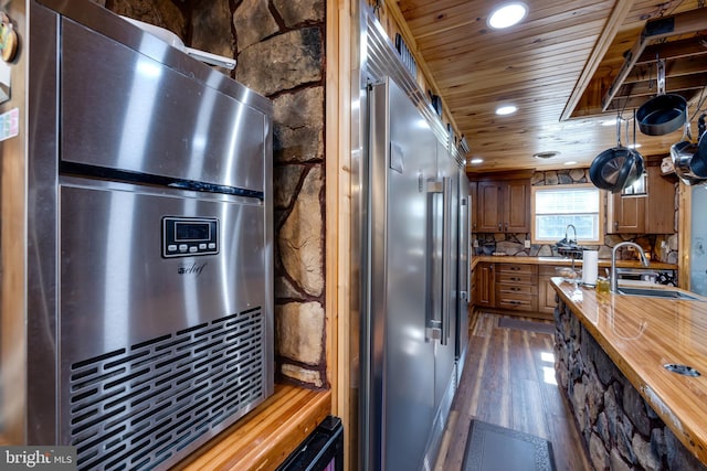 kitchen featuring built in fridge, backsplash, sink, butcher block countertops, and dark hardwood / wood-style flooring