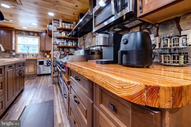 kitchen featuring wood counters, appliances with stainless steel finishes, dark hardwood / wood-style flooring, and tasteful backsplash