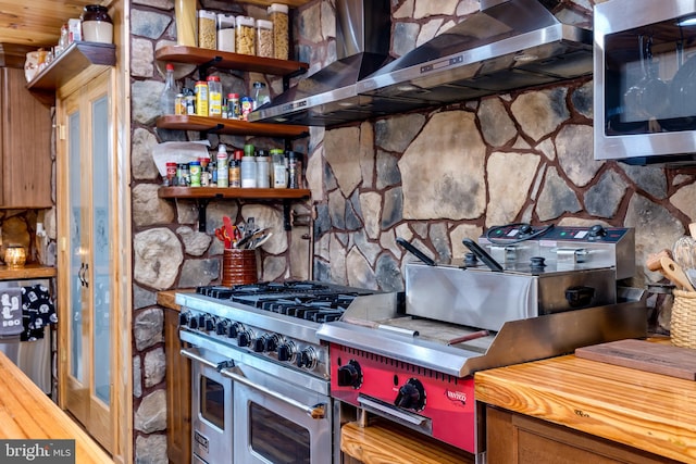 kitchen featuring wall chimney range hood and stainless steel appliances