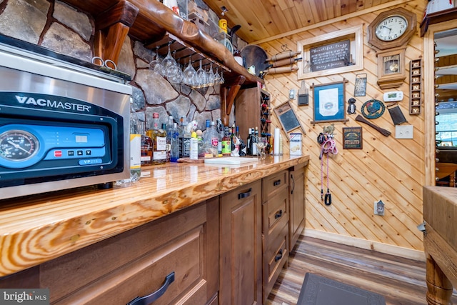 bar featuring wooden walls, butcher block counters, wood ceiling, and wood-type flooring