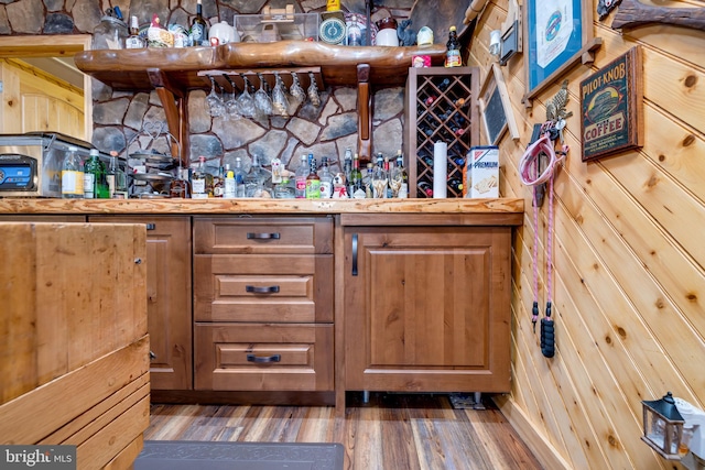 bar with hardwood / wood-style flooring and wooden walls