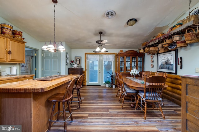 dining area featuring dark hardwood / wood-style floors, ceiling fan with notable chandelier, and vaulted ceiling