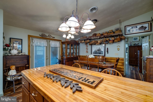 dining area with vaulted ceiling, an inviting chandelier, and dark hardwood / wood-style flooring