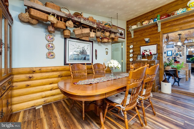 dining area featuring a textured ceiling, rustic walls, and wood-type flooring