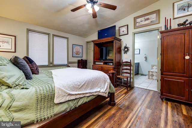 bedroom featuring ensuite bath, dark wood-type flooring, ceiling fan, and vaulted ceiling