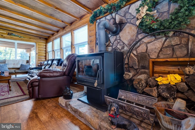 living room with beam ceiling, hardwood / wood-style floors, and a wood stove