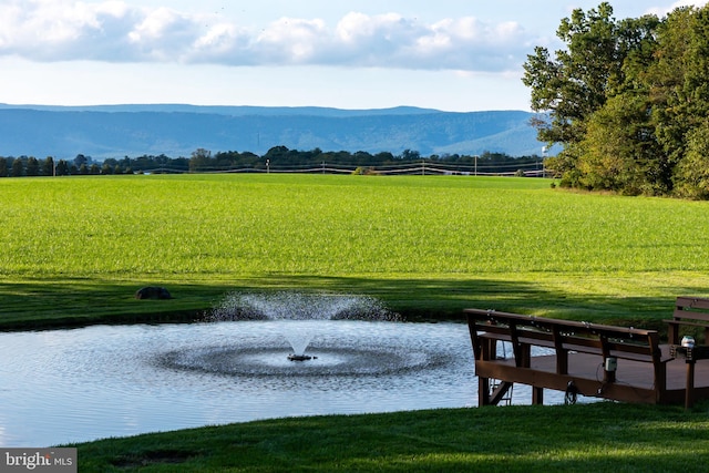 view of community with a rural view, a yard, and a water and mountain view