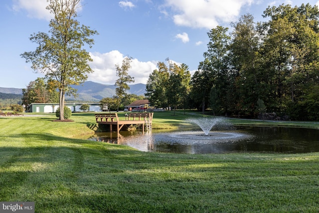 view of property's community featuring a water and mountain view and a lawn