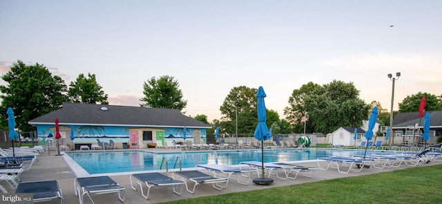 pool at dusk with a patio area