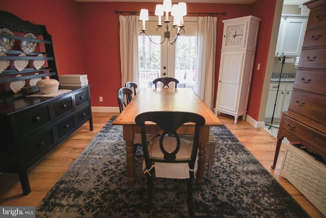 dining area with light hardwood / wood-style floors and a notable chandelier