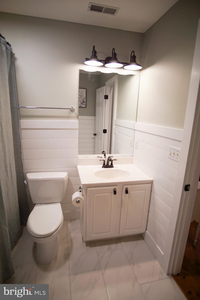 bathroom with tile walls, vanity, curtained shower, and toilet