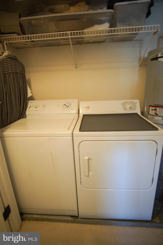 clothes washing area with washing machine and dryer and water heater