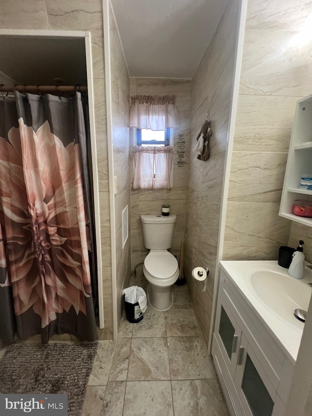 bathroom with tile walls, a shower with curtain, vanity, and toilet