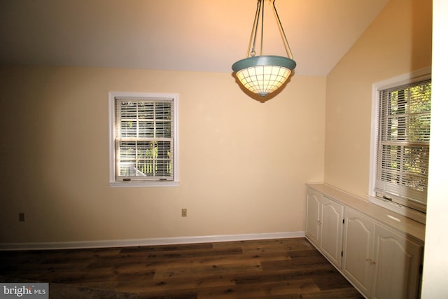 unfurnished dining area featuring dark hardwood / wood-style flooring and vaulted ceiling