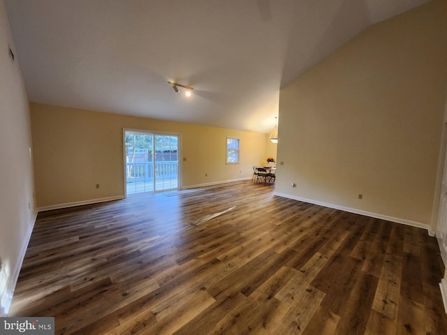 unfurnished living room featuring dark wood-style flooring, baseboards, and vaulted ceiling