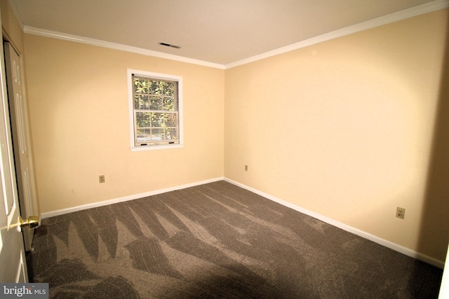 empty room featuring dark colored carpet and crown molding