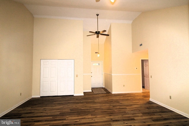 spare room with dark wood-type flooring, ceiling fan, high vaulted ceiling, and baseboards