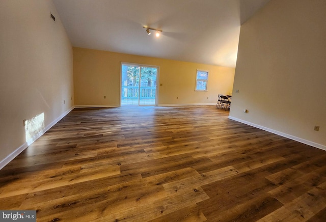 unfurnished living room featuring dark wood finished floors, vaulted ceiling, visible vents, and baseboards