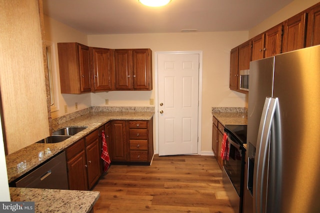 kitchen featuring visible vents, wood finished floors, light stone counters, a sink, and stainless steel appliances