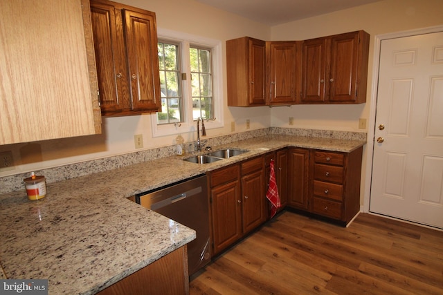 kitchen with light stone countertops, wood finished floors, dishwasher, a sink, and brown cabinets