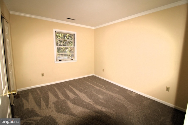 empty room featuring dark carpet, baseboards, ornamental molding, and visible vents