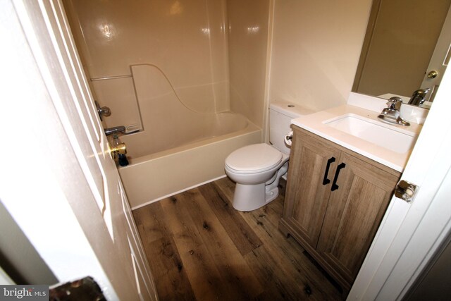 bathroom with wood finished floors, toilet, vanity, and shower / bathtub combination
