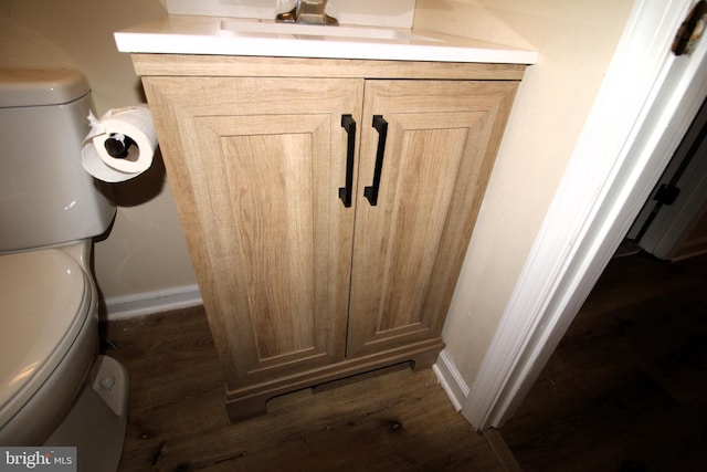 interior details with toilet, vanity, wood finished floors, and baseboards