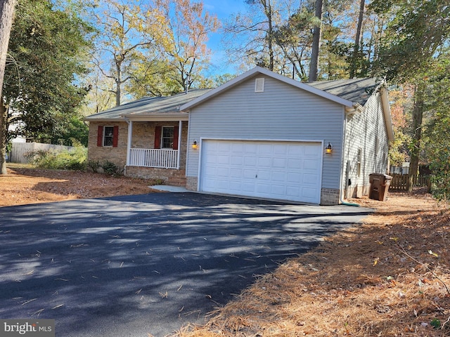 view of front of house featuring driveway, a porch, fence, a garage, and brick siding