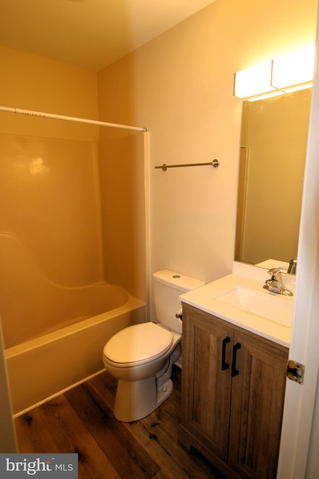 full bath with wood finished floors, toilet, vanity, and bathing tub / shower combination