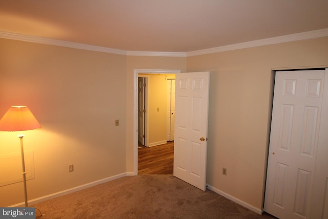 unfurnished bedroom featuring a closet, ornamental molding, and dark colored carpet