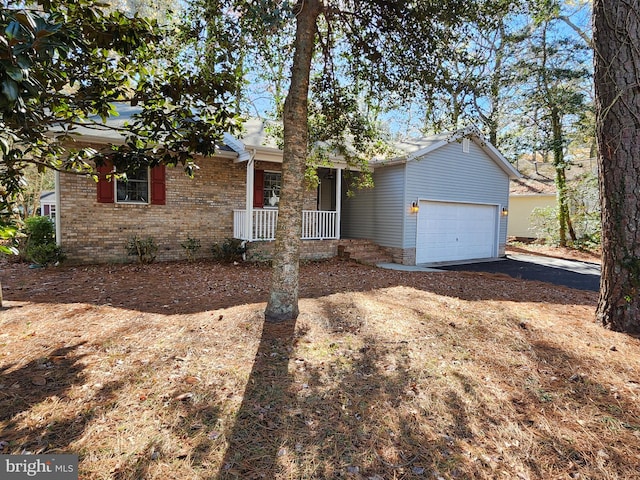 ranch-style house featuring a garage, aphalt driveway, brick siding, and a porch