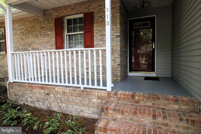 property entrance featuring a porch and brick siding