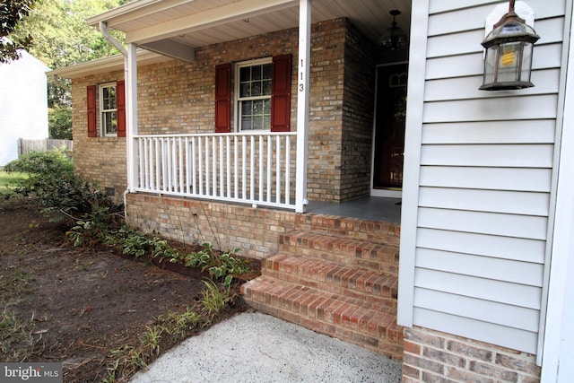 property entrance with a porch and brick siding