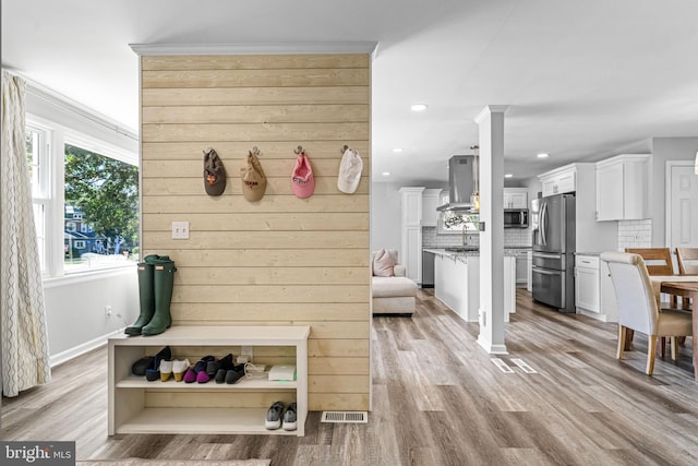 mudroom featuring light wood-type flooring, wooden walls, and sink