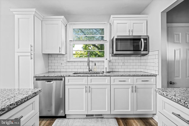 kitchen featuring light stone countertops, stainless steel appliances, white cabinets, dark wood-type flooring, and sink