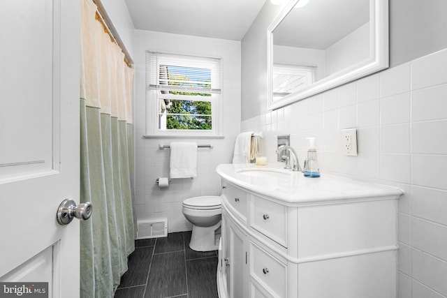 bathroom with toilet, tile walls, vanity, and curtained shower