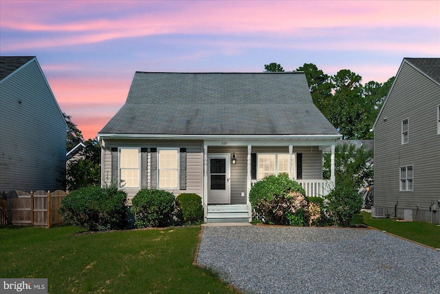 new england style home featuring a porch, a yard, and central AC