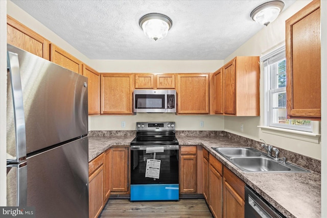 kitchen featuring a textured ceiling, dark hardwood / wood-style flooring, sink, and appliances with stainless steel finishes