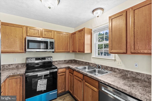 kitchen with a textured ceiling, sink, and stainless steel appliances