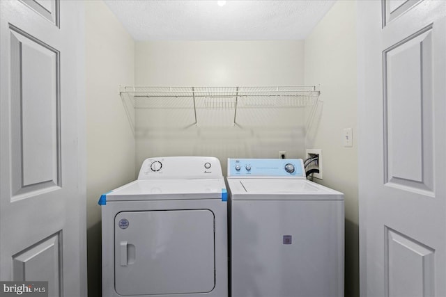 clothes washing area featuring a textured ceiling and washing machine and clothes dryer