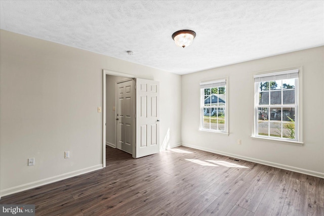 empty room featuring dark hardwood / wood-style flooring and a textured ceiling