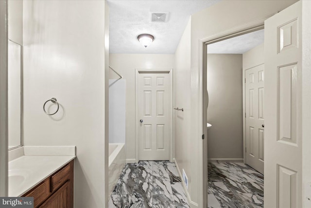 bathroom with vanity, a textured ceiling, and bathing tub / shower combination